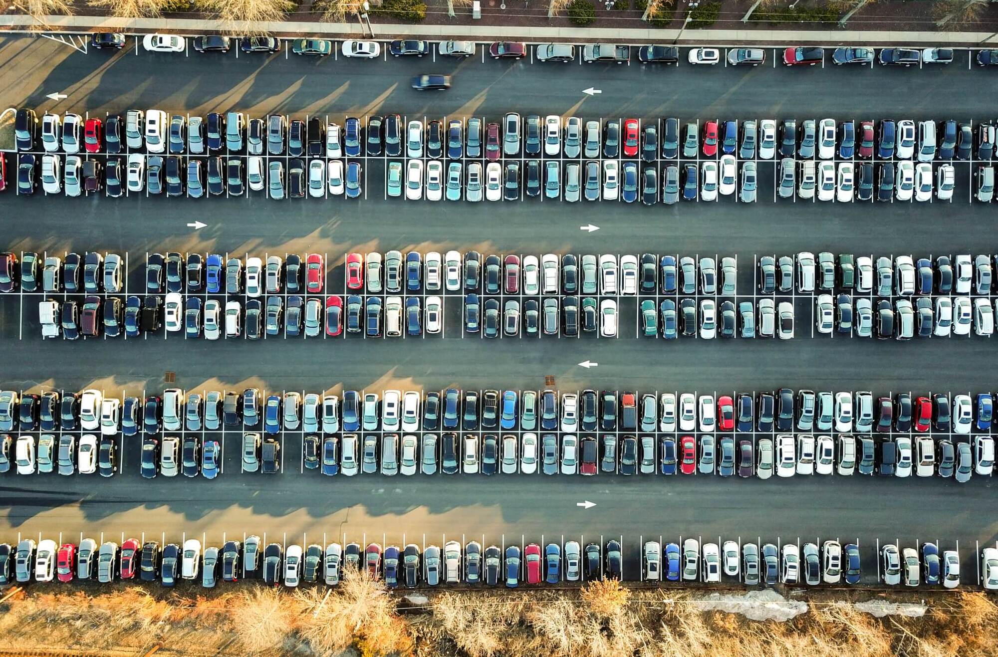 Aerial view of large parking lot with hundreds of cars arranged in rows